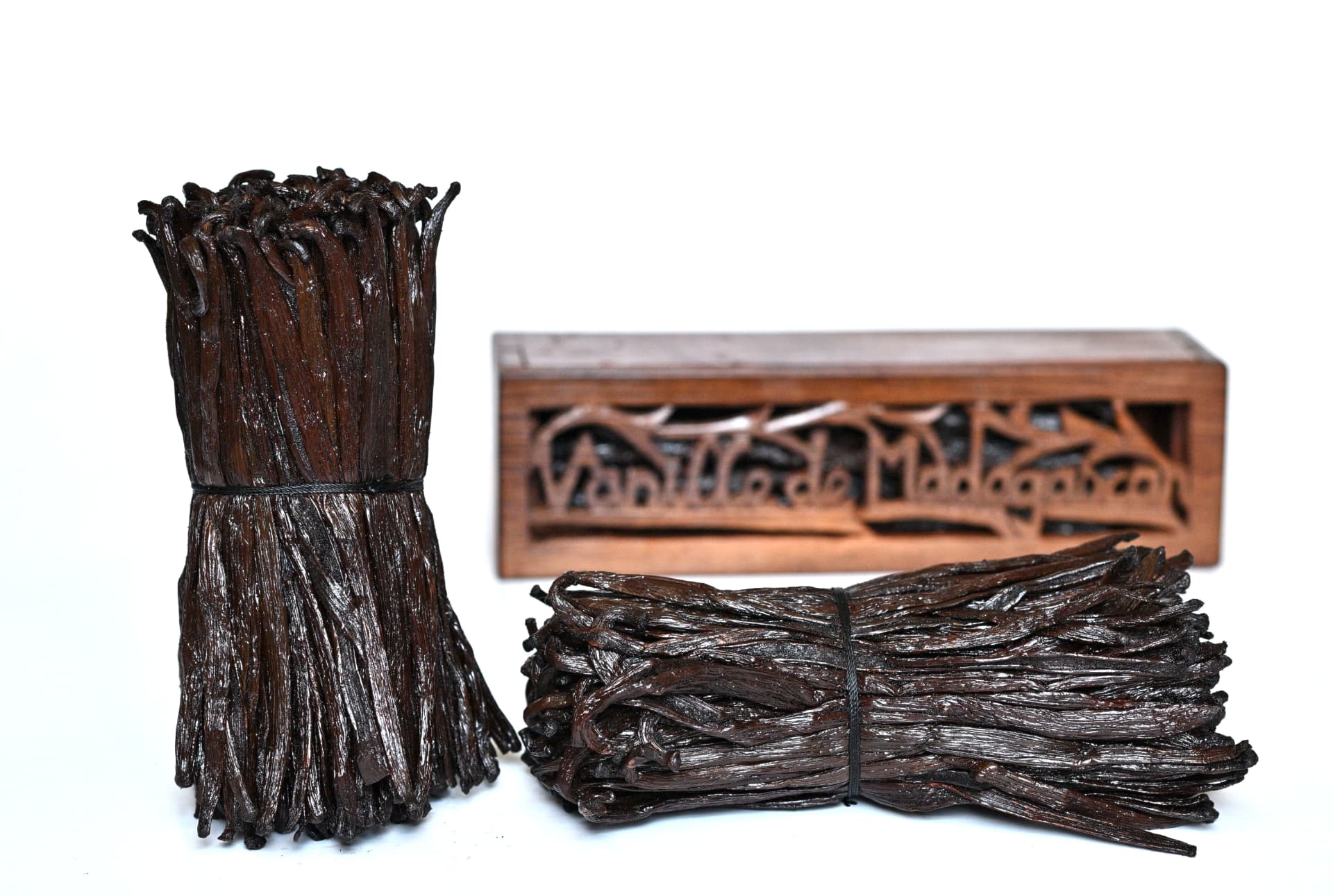 Bundles of split black Madagascar vanilla beans next to a wooden box